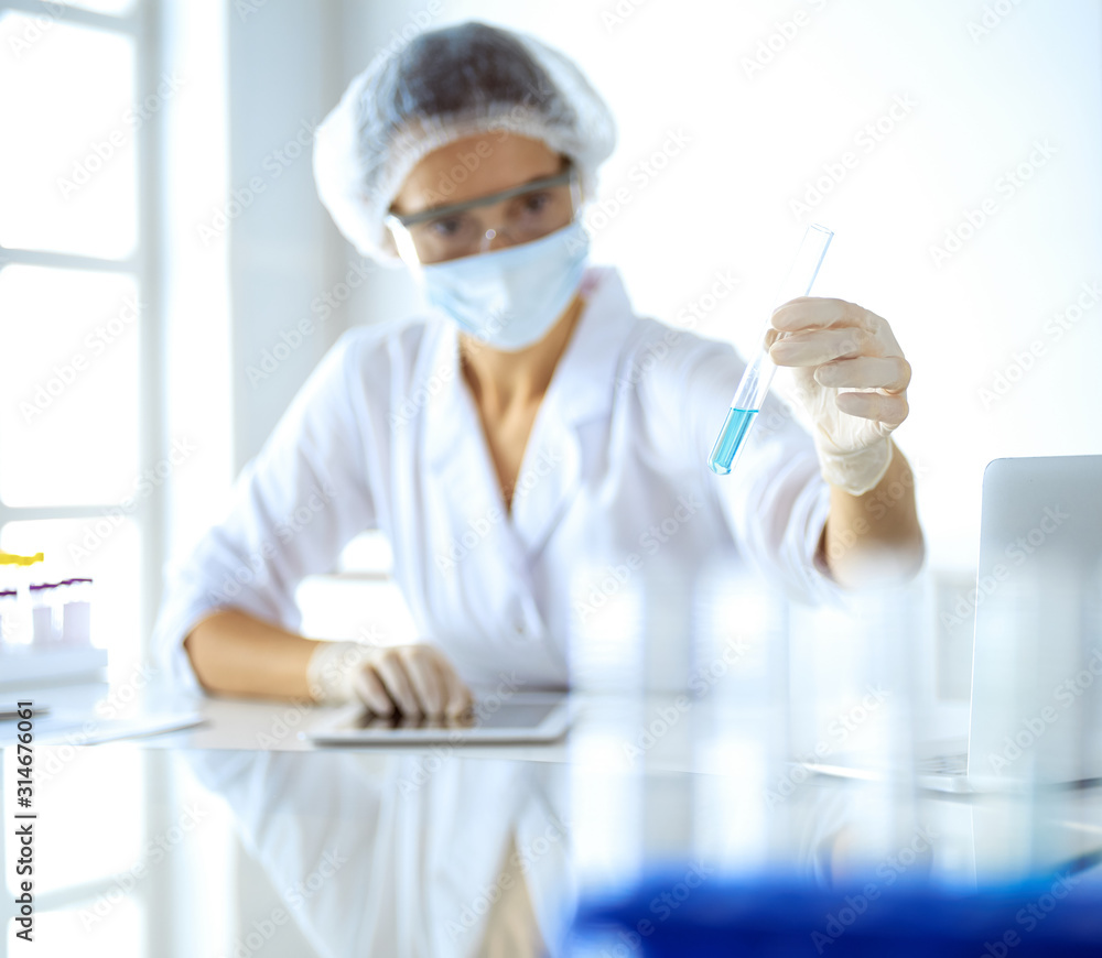 Professional female scientist in protective eyeglasses researching tube with reagents in laboratory. Concepts of medicine and research Professional female scientist in protective eyeglasses researching tube with reagents in laboratory. Concepts of medicine and research