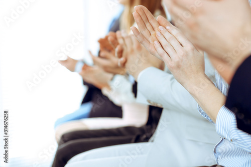 Business people clapping and applause at meeting or conference, close-up of hands. Group of unknown businessmen and women in modern white office. Success teamwork or corporate coaching concept