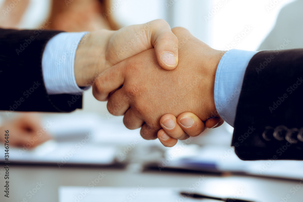 Business people shaking hands at meeting while theirs colleagues clapping and applauding. Group of unknown businessmen and women in modern white office. Success teamwork, partnership and handshake Business people shaking hands at meeting while theirs colleagues clapping and applauding. Group of unknown businessmen and women in modern white office. Success teamwork, partnership and handshake