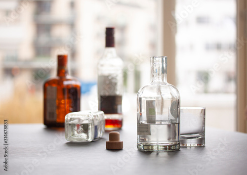 Several liquor bottles standing on a table and one bottle flipped on the table. Selective focus on one bottle. Close up image