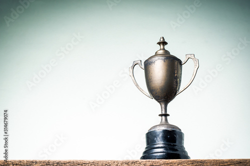 Old trophy on old wooden table with vintage tone light shading background