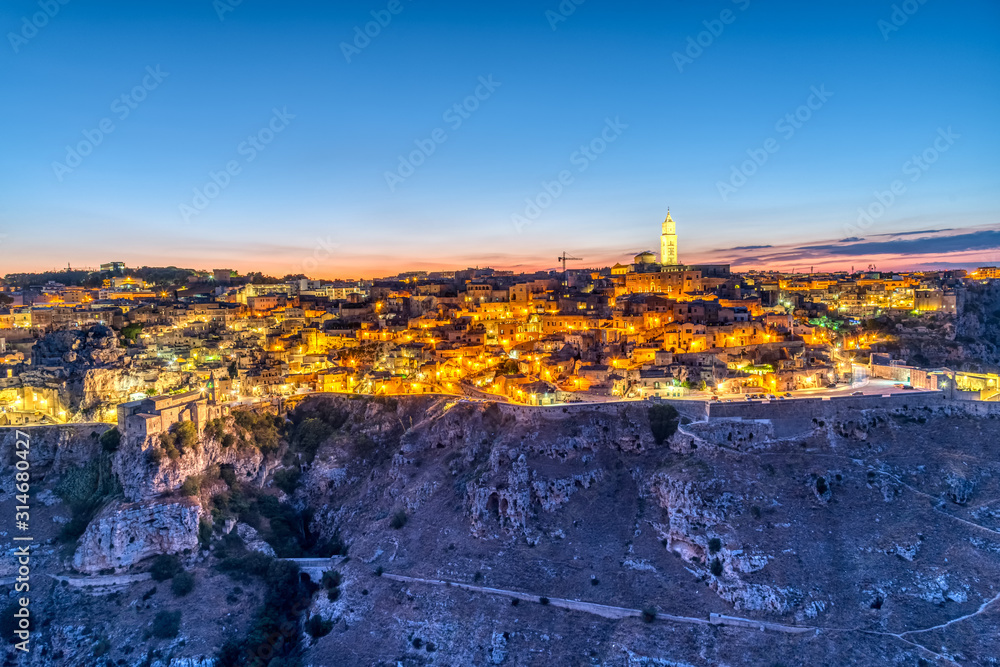 View of the beautiful old town of Matera and the canyon of the Gravina river after sunset