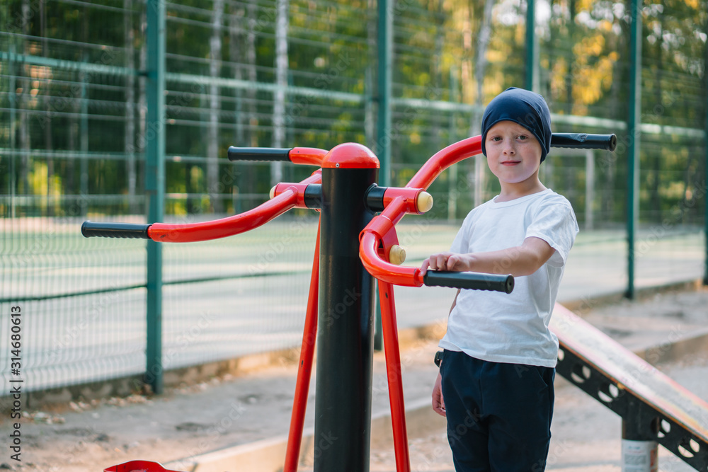 Fototapeta premium Little boy on street public sports training equipment