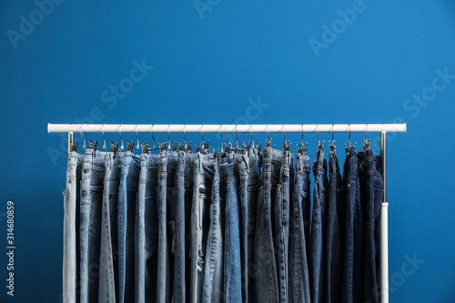 Rack with stylish jeans on blue background