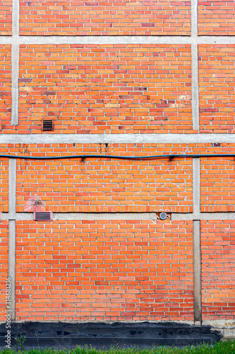 Red brick wall background with green grass