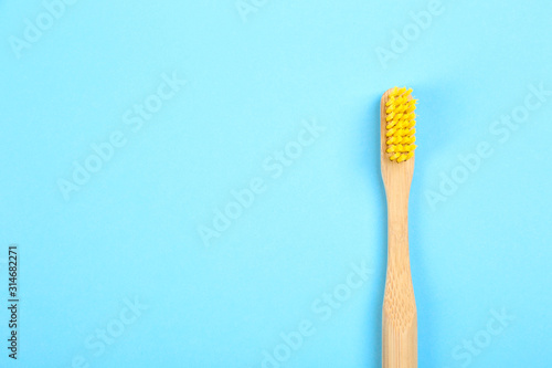 Toothbrush made of bamboo on light blue background  top view. Space for text