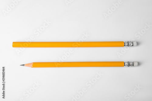 Pencil with point and unsharpened one on white background, top view photo