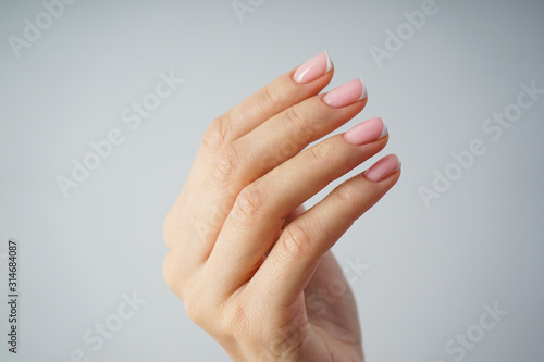 Spa and Manicure concept. Beautiful hand of a young girl with beautiful manicure on a gray background, closeup.