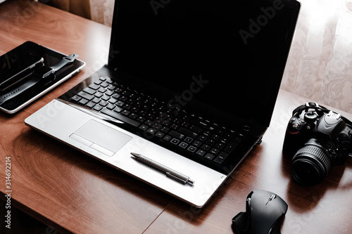 Working space of Photographer or Designer which including of dslr camera lens and wireless mouse on wood desk. Smart Phone, Smart Watch, computer and mouse, tablet for professionals photographer.
