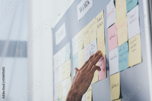 Cropped view of businessman touching sticky notes with letters in office