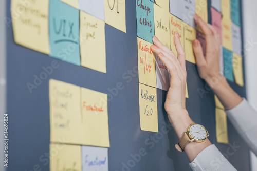 cropped view of businesswoman touching sticky notes with letters in office photo