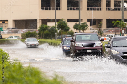 Cars driving trough big water pond after heavy rains fall in Dubai