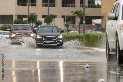 Cars driving trough big water pond after heavy rains fall in Dubai