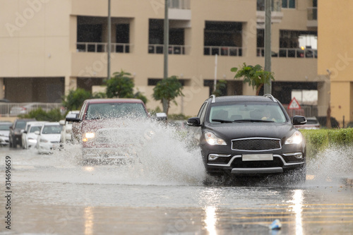 Cars driving trough big water pond after heavy rains fall in Dubai
