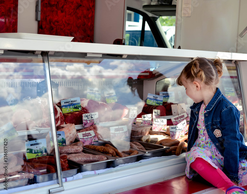 Foto pretty little girl in front of the butcher's window