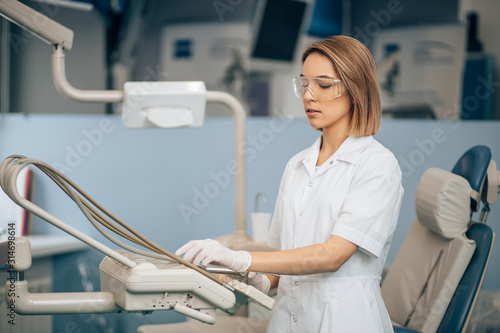 serious concentrated dentist woman at work  use special instrument equipment for teeth treatment  health care provider