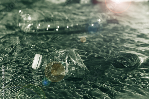 floating plastic bottles on the riverbank with lens flare