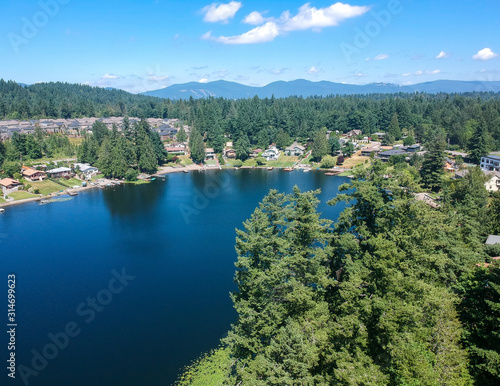 Tranquil Shady Lake on a bright clear day in summertime with trees reflecting in the water a blue sky and white clouds with lily pads dockside in Renton King County Washington State