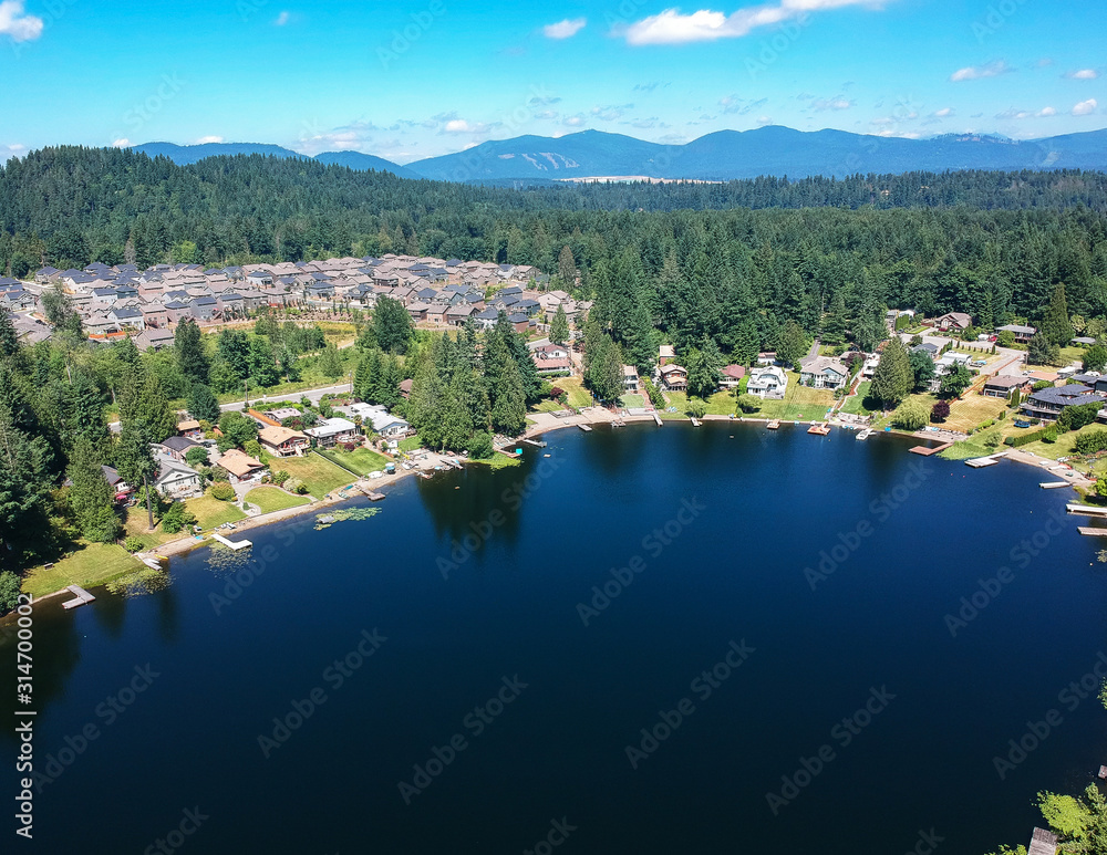 Tranquil Shady Lake on a bright clear day in summertime with trees reflecting in the water a blue sky and white clouds with lily pads dockside in Renton King County Washington State