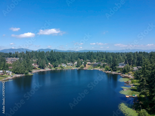 Tranquil Shady Lake on a bright clear day in summertime with trees reflecting in the water a blue sky and white clouds with lily pads dockside in Renton King County Washington State © Marc Sanchez