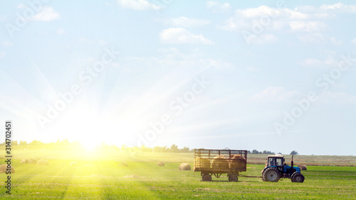 Tractor loading hay bales on truck agricultural works photo