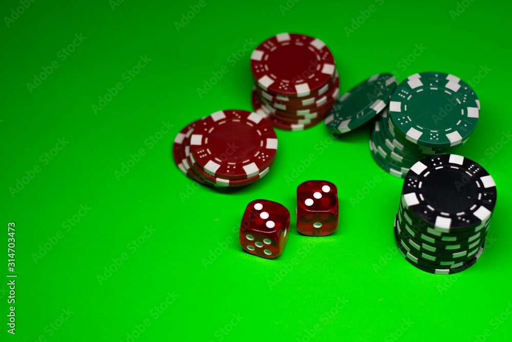Gambling chips and game dice on the green poker cloth Gambling chips and game dice on the green poker cloth