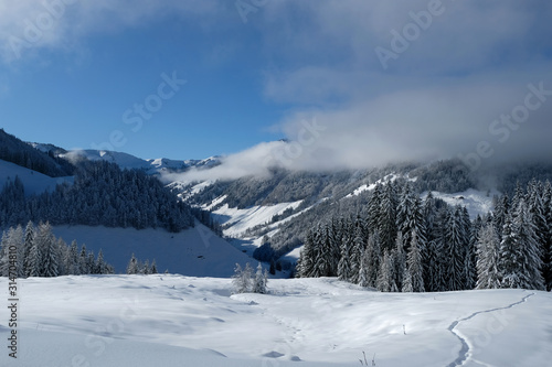 Beautiful panorama of snow covered Kitzbuehleler Horn, Austrian alps mountain peak. Low clouds hang around the mountain ranges and over the valley. Glittering shiny deep fresh powder snow foreground. © Fotorina