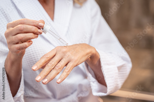 Woman applying cosmetic oil on her hand