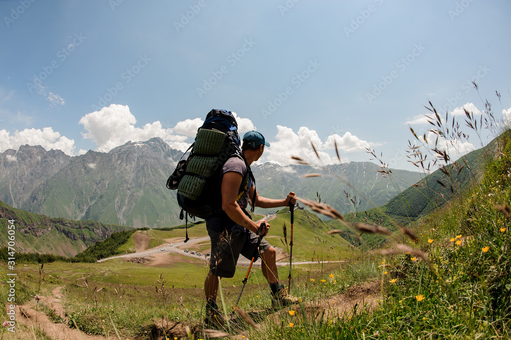Fototapeta premium Hiker with backpack travels among hills and mountains