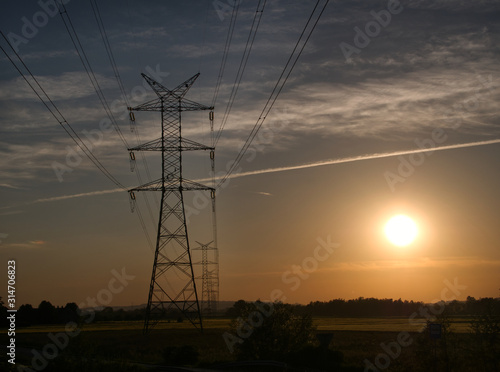 Linie przesyłowe energii elektrycznej wysokiego napięcia na tle wieczornego nieba