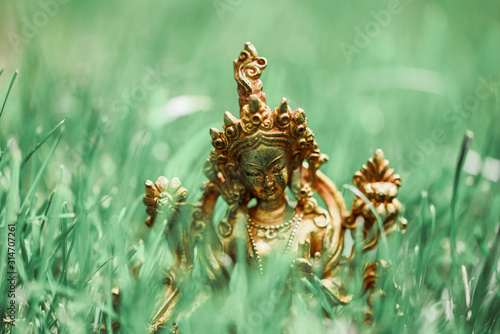 Figure of a female Buddhist deity (Green Tara) sitting on a lawn 