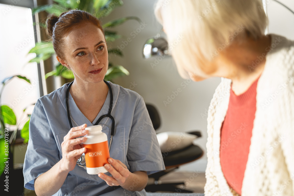 Charming brunette practitioner showing bottle with glycine Charming brunette practitioner showing bottle with glycine
