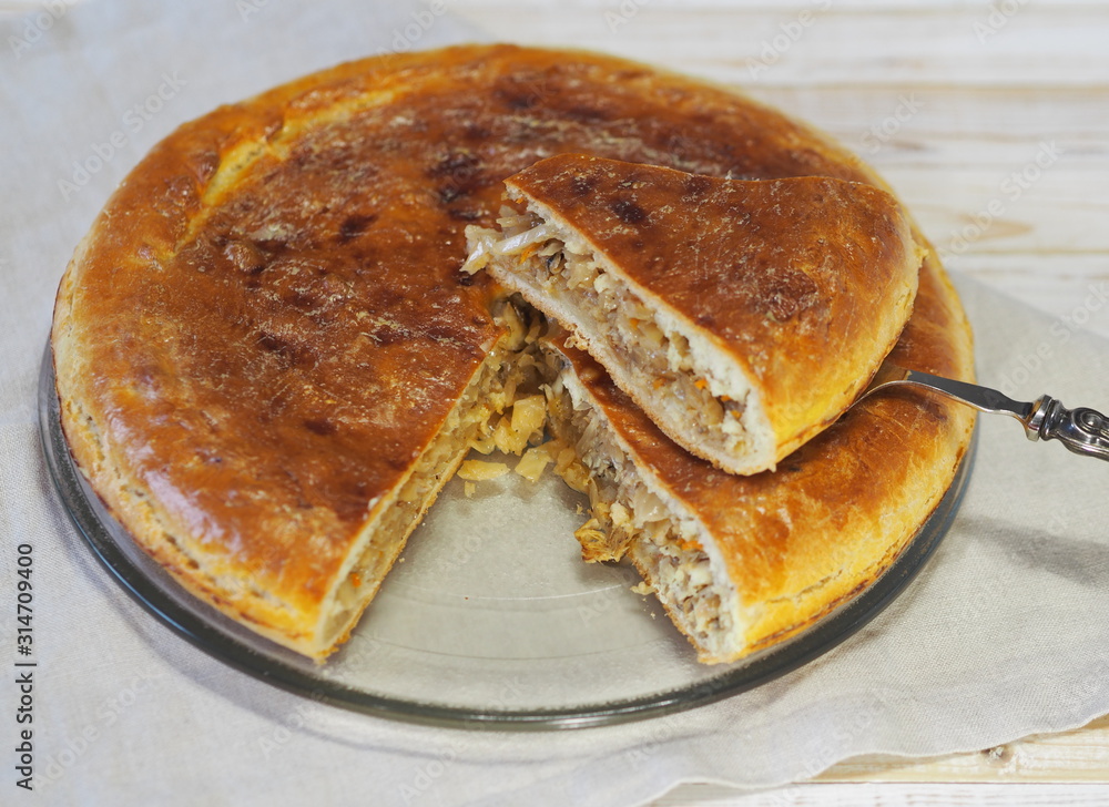 Round homemade pie with cabbage and river fish pike. Wooden rustic white table. Homemade food. Round homemade pie with cabbage and river fish pike. Wooden rustic white table. Homemade food.