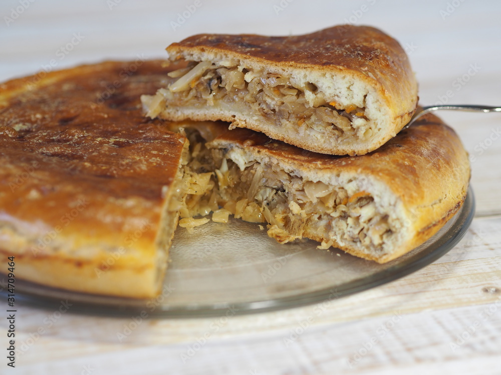 Round homemade pie with cabbage and river fish pike. Wooden rustic white table. Homemade food. Round homemade pie with cabbage and river fish pike. Wooden rustic white table. Homemade food.