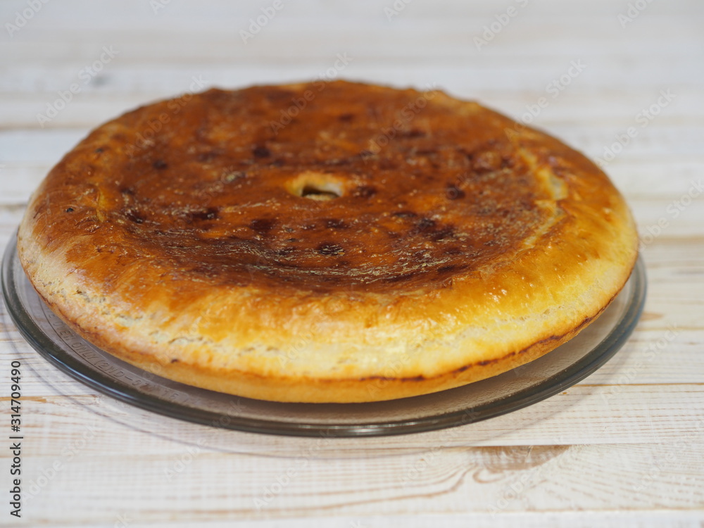Round homemade pie with cabbage and river fish pike. Wooden rustic white table. Homemade food. Round homemade pie with cabbage and river fish pike. Wooden rustic white table. Homemade food.