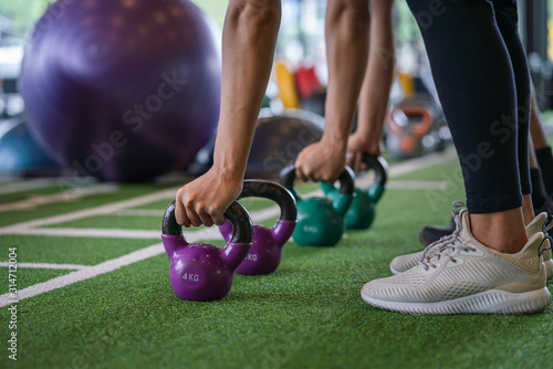 Group of athletic young man and woman workout training and exercise with kettlebell weight at fitness gym sport club