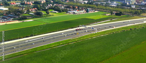 aerial shot with tilt-shift focus effect of a highway crossing through the countryside and green lands