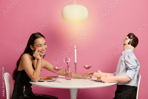 Affectionate woman makes korean like sign  stretches hand to lover  pose at festive dinner table  expresses love to imaginary boyfriend  enjoy lunch time and communication  romantic atmosphere