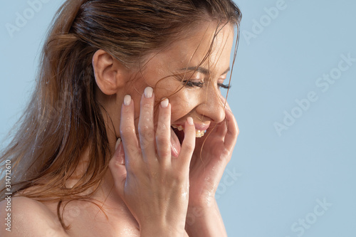 Wash your face and take care of your skin. Young woman washes her face and laughs