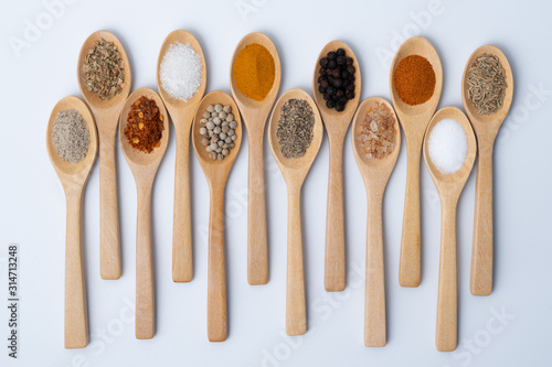 Various spices in wooden spoons, isolated background