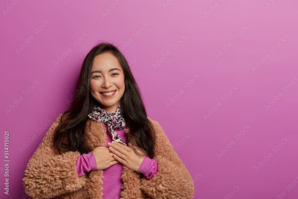 Thank you for so sweet words. Tender Korean woman happy to get present, keeps hands on heart, appreciates efforts, dressed in winter fur coat, isolated over purple background. Acknowledgement Thank you for so sweet words. Tender Korean woman happy to get present, keeps hands on heart, appreciates efforts, dressed in winter fur coat, isolated over purple background. Acknowledgement