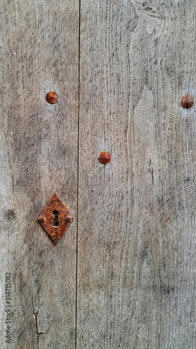 Vintage wooden door with rusty keyhole and rivets