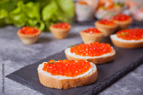 Fresh red caviar on bread on the black plate. Sandwiches with red caviar.