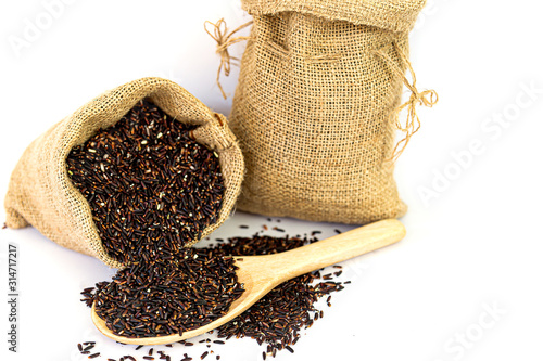 Riceberry In a wooden spoon and in a sackcloth isolated on white background