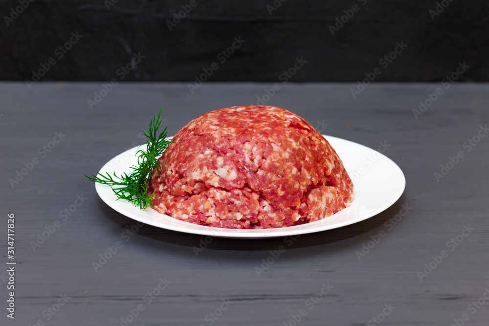 Plate with fresh raw ground beef. Sprig of dill Plate with fresh raw ground beef. Sprig of dill