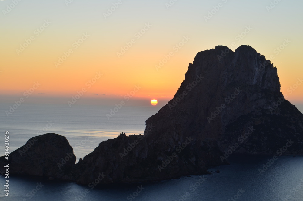 sol despidiendose en el horizonte del mar mediterraneo entre los islotes de ibiza