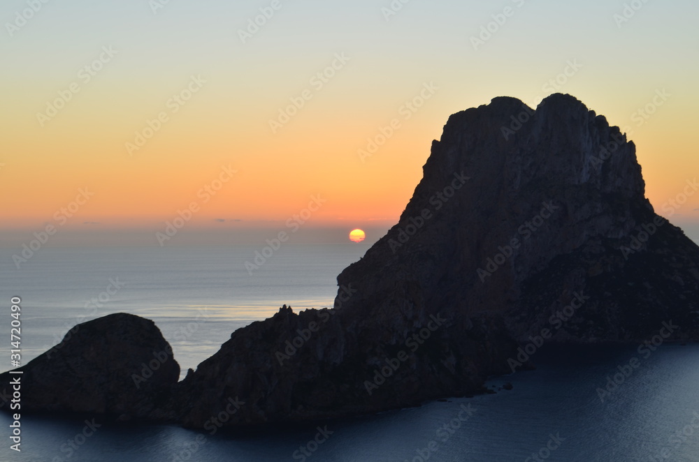 sol despidiendose en el horizonte del mar mediterraneo entre los islotes de ibiza