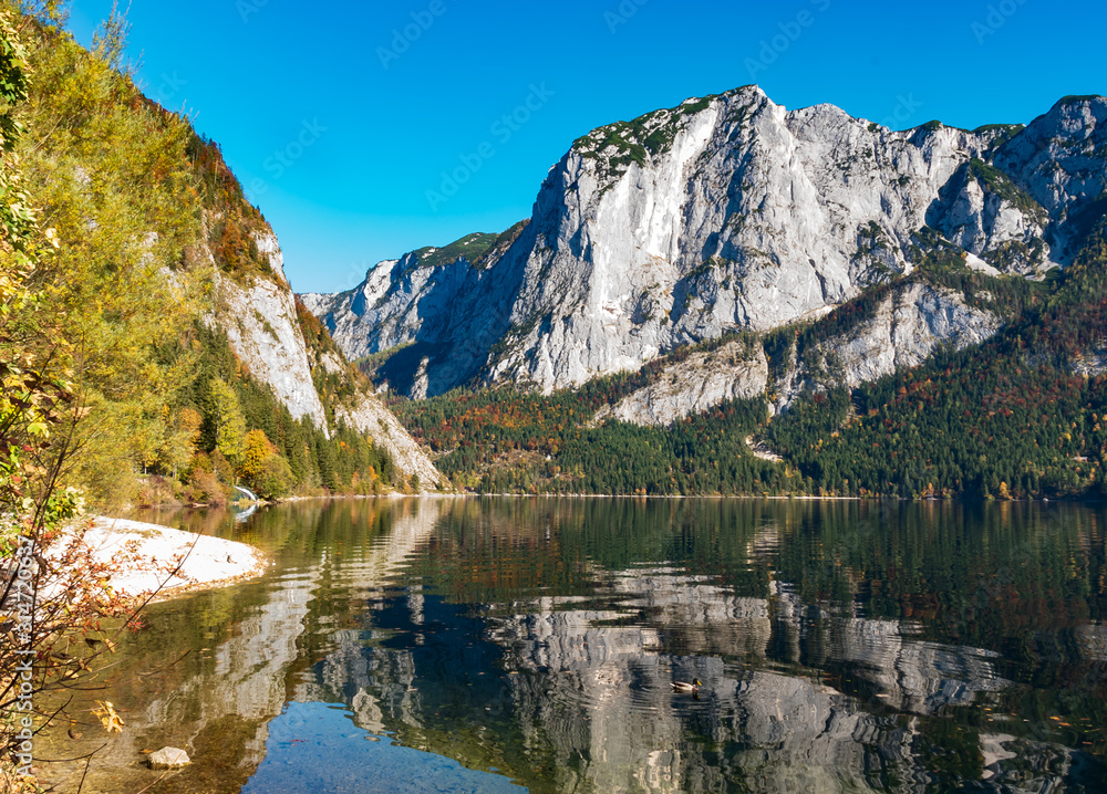 Altaussee, Styria, Austria - A view over Lake Altaussee to the Trisselwand, part of the Totes Gebirge, on a sunny cloudless day in golden October with blue skies.