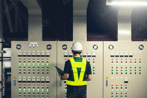 Electrical Engineer team working front control panel, Technician daily check control panel in service room in factory. photo