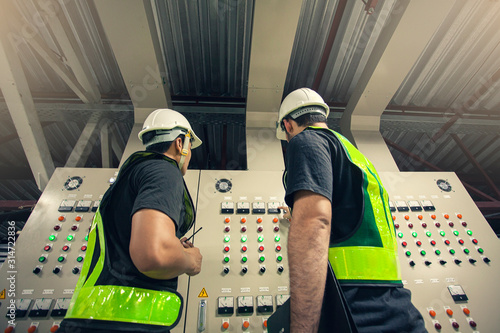 Two Electrical Engineer team working front control panel, Engineer training job with control panel in service room.
